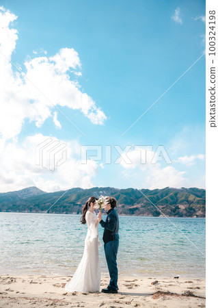 Newlyweds taking wedding photos on the beach 100324198