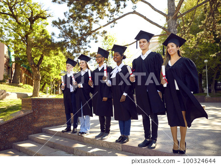 Happy, smart and proud multiracial graduates men and women stand in row during graduation ceremony. Happy, smart and proud multiracial graduates men and women stand in row during graduation ceremony. 100324644