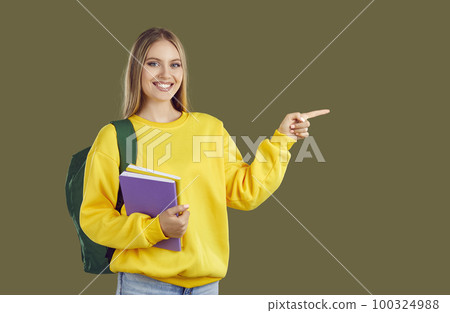 Happy student girl with backpack and copybooks pointing finger on copy space on khaki background. Happy student girl with backpack and copybooks pointing finger on copy space on khaki background. 100324988