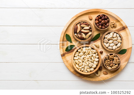 mixed nuts in wooden bowl. Mix of various nuts on colored background. pistachios, cashews, walnuts, hazelnuts, peanuts and brazil nuts mixed nuts in wooden bowl. Mix of various nuts on colored background. pistachios, cashews, walnuts, hazelnuts, peanuts and brazil nuts 100325292