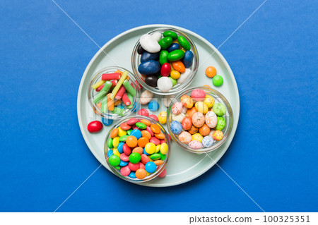 Multicolored candies in a bowl on a colored background. birthday and holiday concept. Top view with copy space 100325351