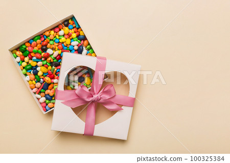 Box with sweet chocolate candies on color background, Various candy sweets. Valentines day gift box. Top view flat lay with copy space Box with sweet chocolate candies on color background, Various candy sweets. Valentines day gift box. Top view flat lay with copy space 100325384