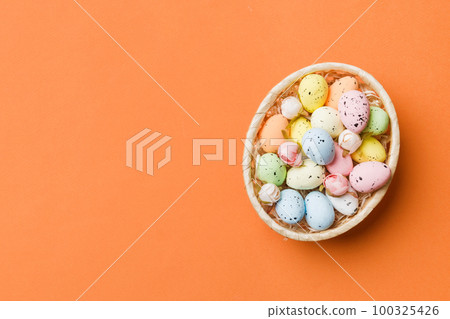 Colorful Easter eggs in wicker basket against colored background, closeup. top view with copy space Colorful Easter eggs in wicker basket against colored background, closeup. top view with copy space 100325426