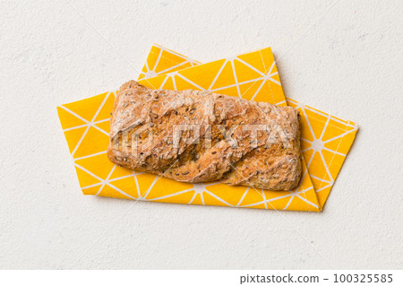 Fresh loaves of bread with wheat and gluten on a colored table. bread on napkin on rustic background, fresh bread top view 100325585