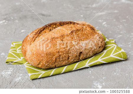 freshly baked bread with napkin on rustic table top view. Healthy white bread loaf isolated 100325588