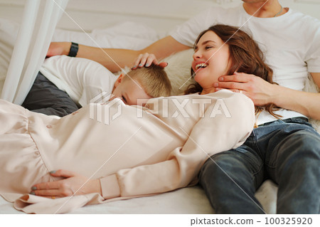 Happy pregnant mom, dad and son play in bed. the concept of family happiness. 100325920