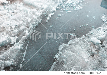 Spring stream, ice and snow, dazzling sunlight, reflection of sky in water 100326216