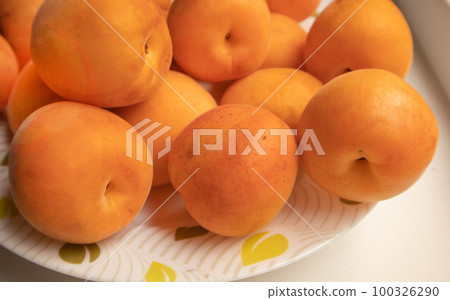 A bunch of fresh ripe apricots on a plate, close-up, shallow depth of field 100326290