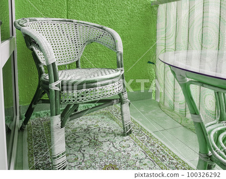 Balcony interior with stylish wicker chair, vintage, close-up, green tinting 100326292