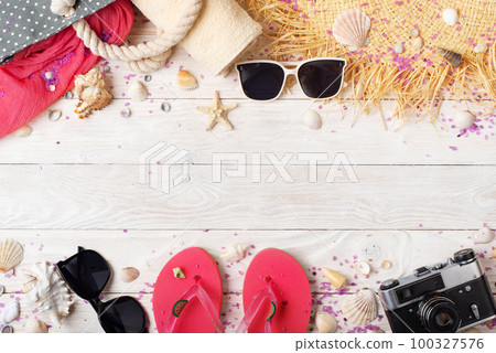 Camera straw hat sunglasses flip flops and beach bag on white wooden background 100327576