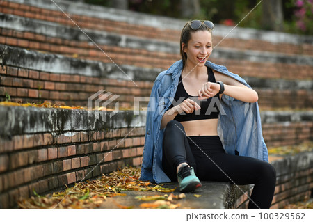 Shot of happy brunette sporty woman dressed in sportswear checks fitness results on smartwatch Shot of happy brunette sporty woman dressed in sportswear checks fitness results on smartwatch 100329562