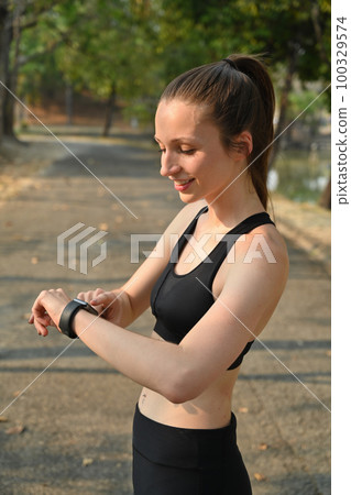 Sport caucasian woman in sportswear looking smart watch checking result jogging in city park outdoor Sport caucasian woman in sportswear looking smart watch checking result jogging in city park outdoor 100329574