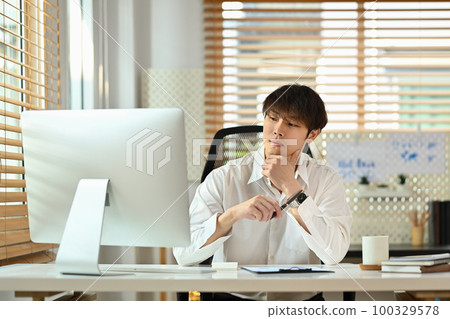 Millennial asian male marketing business manager expert looking at computer monitor, working in his personal office 100329578