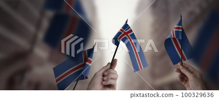 A group of people holding small flags of the Iceland in their hands A group of people holding small flags of the Iceland in their hands 100329636