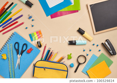Flat lay photo of workspace desk with school accessories or office supplies on pink background. 100329814