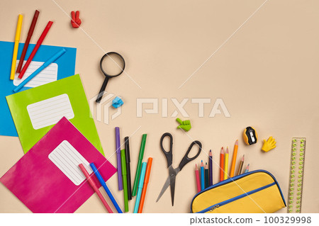 Flat lay photo of workspace desk with school accessories or office supplies on pink background. 100329998
