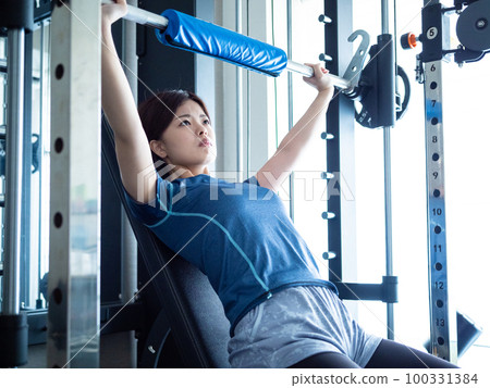 Woman bench pressing on a power rack 100331384