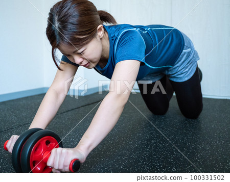 A woman pushing with an abdominal muscle roller A woman pushing with an abdominal muscle roller 100331502