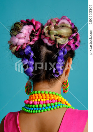 Lovely girl with a multi-colored braids hairstyle and bright make-up, posing in studio against a blue background. Lovely girl with a multi-colored braids hairstyle and bright make-up, posing in studio against a blue background. 100333505