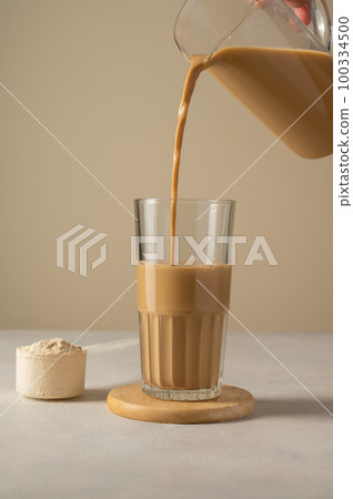 Protein powder and. Pouring chocolate drink in a glass. Protein powder and. Pouring chocolate drink in a glass. 100334500