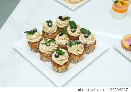 Cupcakes with cheese pistachio cream in a candy bar decorated with blueberries and mint Cupcakes with cheese pistachio cream in a candy bar decorated with blueberries and mint 100334617