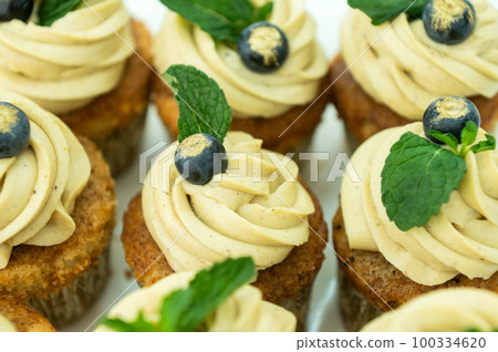 Cupcakes with cheese pistachio cream in a candy bar decorated with blueberries and mint in a plate Cupcakes with cheese pistachio cream in a candy bar decorated with blueberries and mint in a plate 100334620