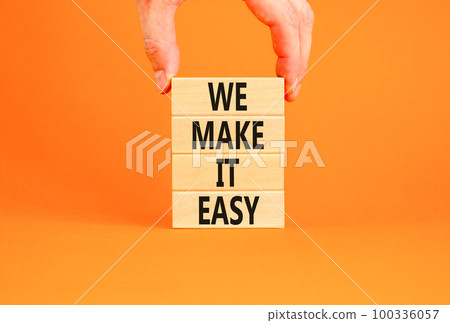 We make it easy symbol. Concept words We make it easy on wooden cubes. Beautiful orange table orange background. Businessman hand. Business motivational we make it easy concept. Copy space. 100336057