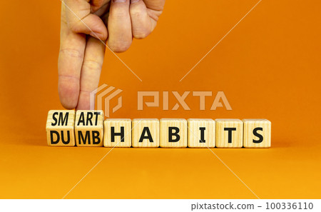 Smart or dumb habits symbol. Concept word Smart habits and Dumb habits on wooden cubes. Beautiful orange table orange background. Businessman hand. Business smart or dumb habits concept. Copy space. Smart or dumb habits symbol. Concept word Smart habits and Dumb habits on wooden cubes. Beautiful orange table orange background. Businessman hand. Business smart or dumb habits concept. Copy space. 100336110