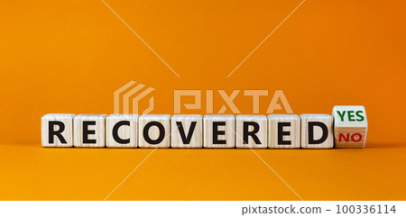 Turned a cube and changed the words 'recovered no' to 'recovered yes' on wooden cubes. Beautiful orange background, copy space. Business concept. Turned a cube and changed the words 'recovered no' to 'recovered yes' on wooden cubes. Beautiful orange background, copy space. Business concept. 100336114