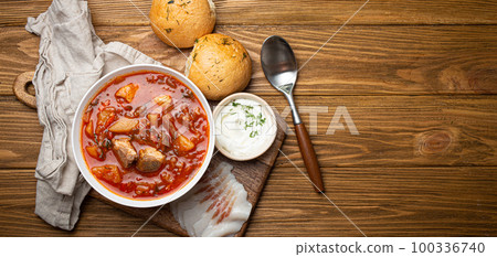 Ukrainian Borscht, red beetroot soup with meat, in white bowl with sour cream, garlic buns Pampushka and salo slices, rustic stone background. Traditional authentic dish of Ukraine, space for text Ukrainian Borscht, red beetroot soup with meat, in white bowl with sour cream, garlic buns Pampushka and salo slices, rustic stone background. Traditional authentic dish of Ukraine, space for text 100336740