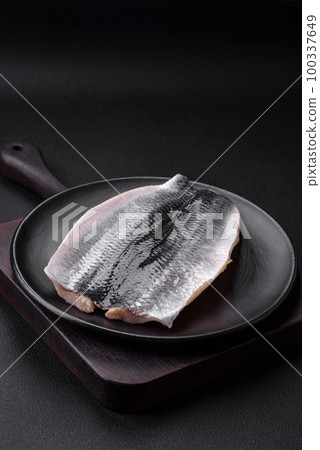 Delicious salted herring fillet in oil on a black ceramic plate Delicious salted herring fillet in oil on a black ceramic plate 100337649