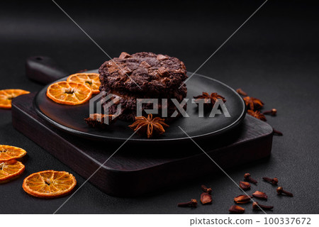 Delicious fresh oatmeal round cookies with chocolate on a black ceramic plate Delicious fresh oatmeal round cookies with chocolate on a black ceramic plate 100337672