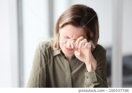 Exhausted, tired female manager sitting with her eyes closed at her desk in office. 100337786