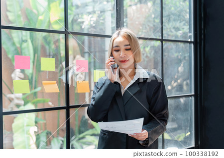 Portrait of a Happy business woman talking with a cell phone in hand holding documents Portrait of a Happy business woman talking with a cell phone in hand holding documents 100338192