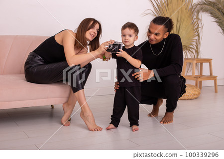 happy family in black clothes, sitting on floor in the light living room, play with old camera happy family in black clothes, sitting on floor in the light living room, play with old camera 100339296