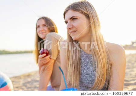 Two young beautiful women are having fun on beach and smiling Two young beautiful women are having fun on beach and smiling 100339677