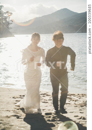 新娘和新郎在沙灘上奔跑 新娘和新郎在沙灘上奔跑 100339685