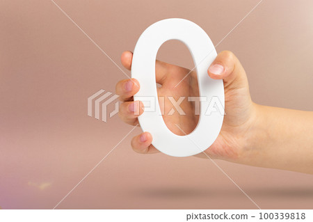 Numeral zero in hand. A hand holds a white number zero on a red background with copy space. Zero concept, 0 percent interest rate, minimum air emissions, cost or credit no increase. Numeral zero in hand. A hand holds a white number zero on a red background with copy space. Zero concept, 0 percent interest rate, minimum air emissions, cost or credit no increase. 100339818
