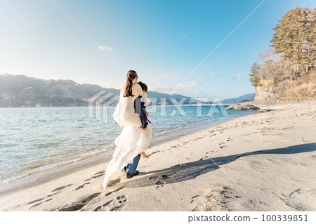 Bride and groom on their backs on the sandy beach 100339851
