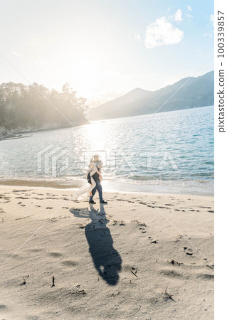Bride and groom on their backs on the sandy beach 100339857