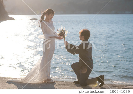 A man proposing to a woman on the beach with a bouquet A man proposing to a woman on the beach with a bouquet 100341029