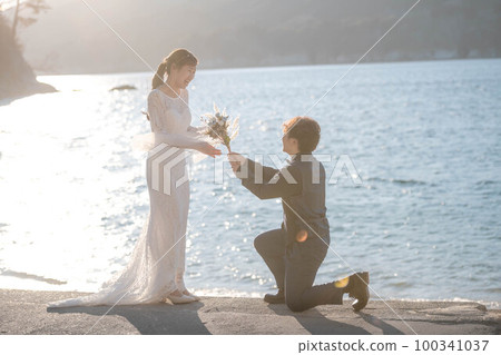 A man proposing to a woman on the beach with a bouquet A man proposing to a woman on the beach with a bouquet 100341037