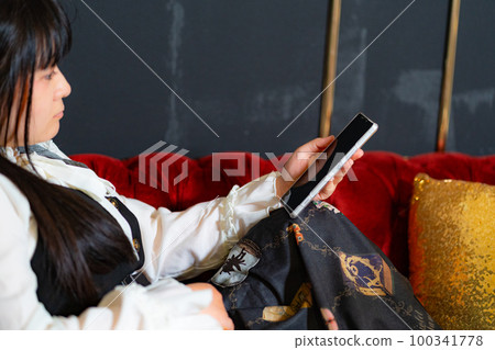A woman using a smartphone on a sofa A woman using a smartphone on a sofa 100341778