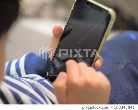 A child operating a smartphone in the living room 100345041