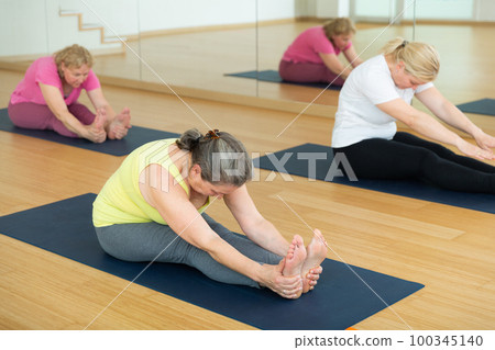 Ladies are doing seating forward bend Ladies are doing seating forward bend 100345140