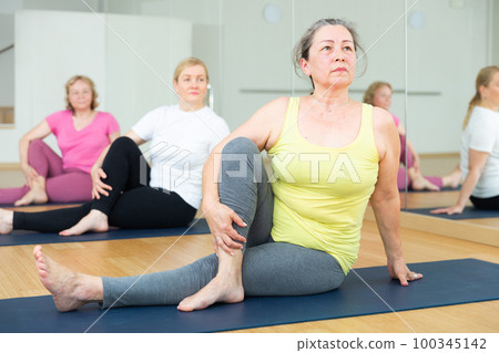 People practicing stretching yoga training in class - marichiasana pose People practicing stretching yoga training in class - marichiasana pose 100345142