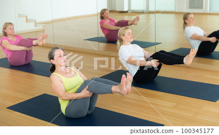 Women are doing boat pose 100345177