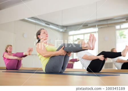 People relaxing and enjoying yoga elements - boat pose People relaxing and enjoying yoga elements - boat pose 100345189