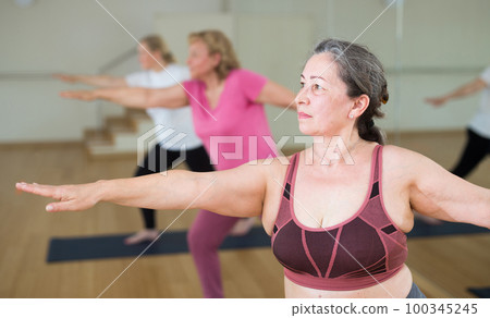 Women practicing yoga - virabhadrasana pose Women practicing yoga - virabhadrasana pose 100345245