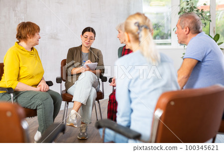 Young female tutor leading educational class for group of elderly 100345621